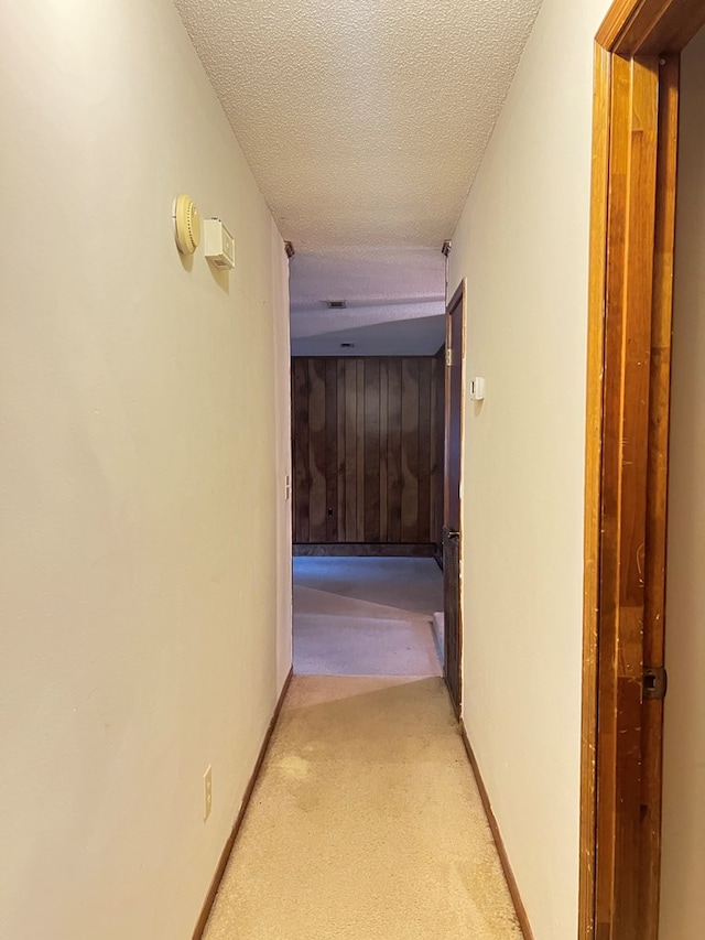 corridor featuring a textured ceiling and light colored carpet