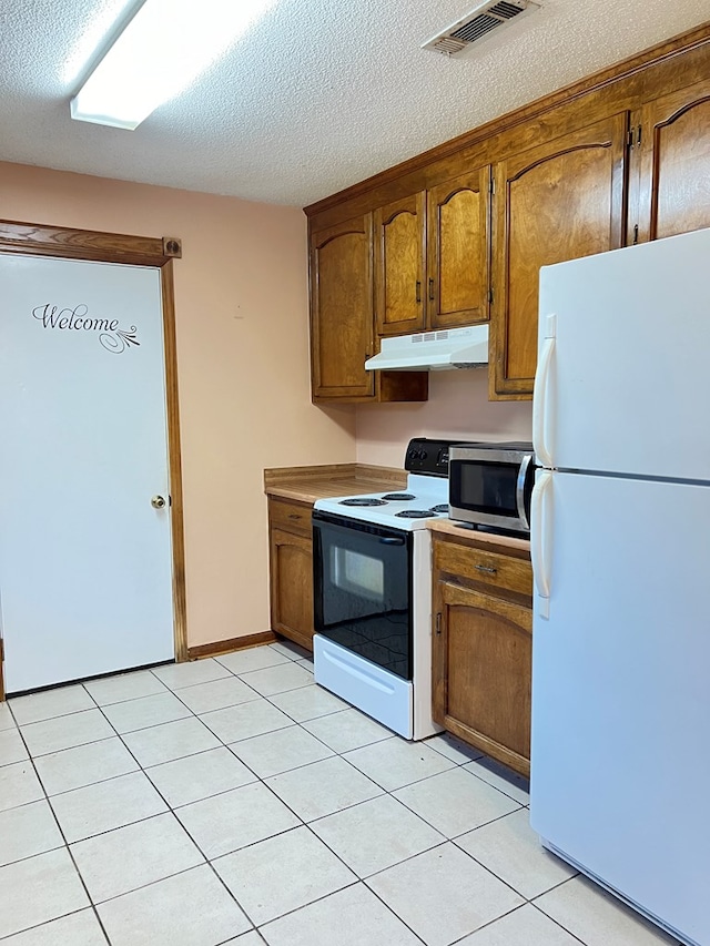 kitchen featuring a textured ceiling, white appliances, and light tile patterned flooring