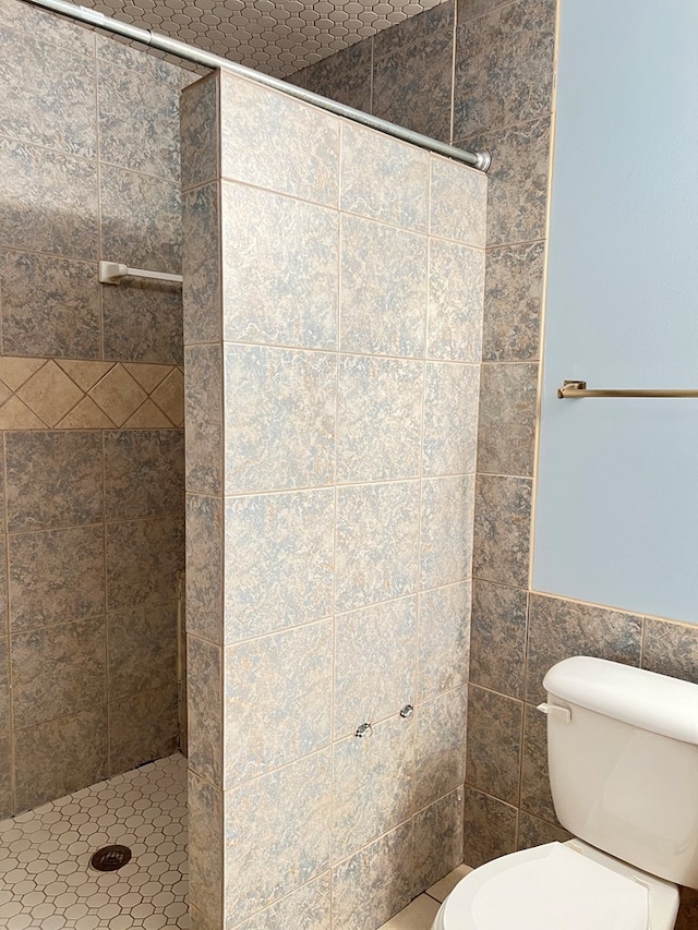 bathroom featuring toilet, tile walls, and tiled shower