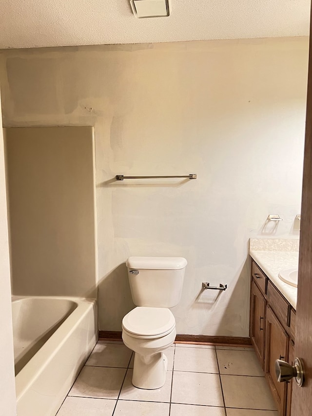 bathroom featuring tile patterned floors, vanity, toilet, and a tub to relax in