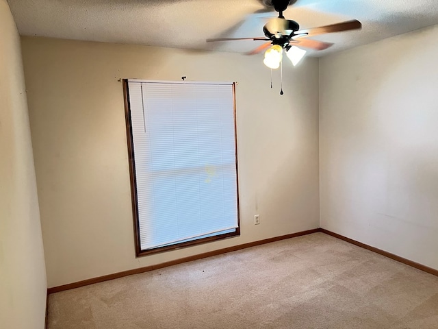 empty room with ceiling fan, a textured ceiling, and light carpet