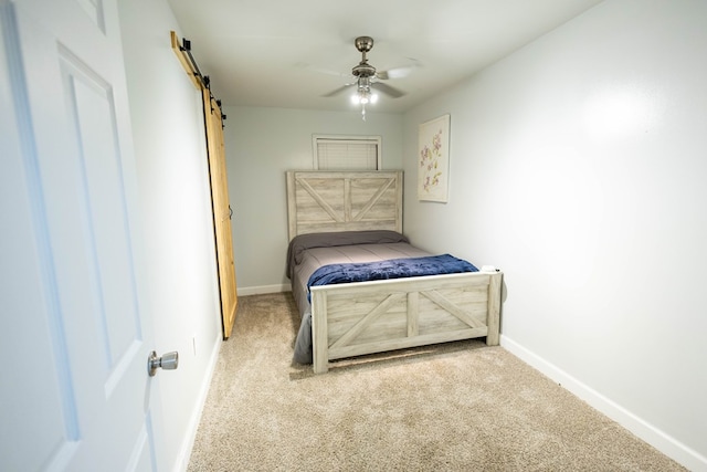 bedroom featuring a barn door, ceiling fan, and light carpet