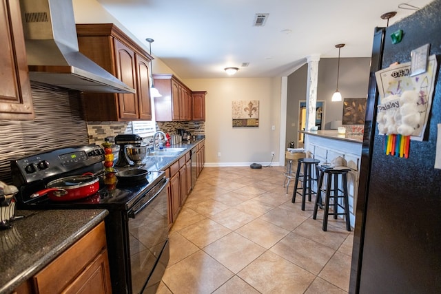 kitchen featuring black appliances, sink, hanging light fixtures, wall chimney exhaust hood, and dark stone countertops