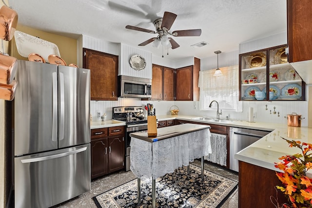 kitchen with sink, ceiling fan, a textured ceiling, decorative light fixtures, and stainless steel appliances