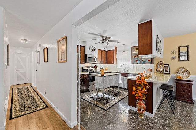 kitchen featuring kitchen peninsula, a kitchen breakfast bar, a textured ceiling, stainless steel appliances, and sink