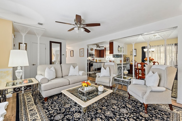 living room with wood-type flooring and ceiling fan with notable chandelier