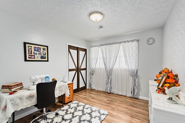 home office featuring light hardwood / wood-style floors and a textured ceiling