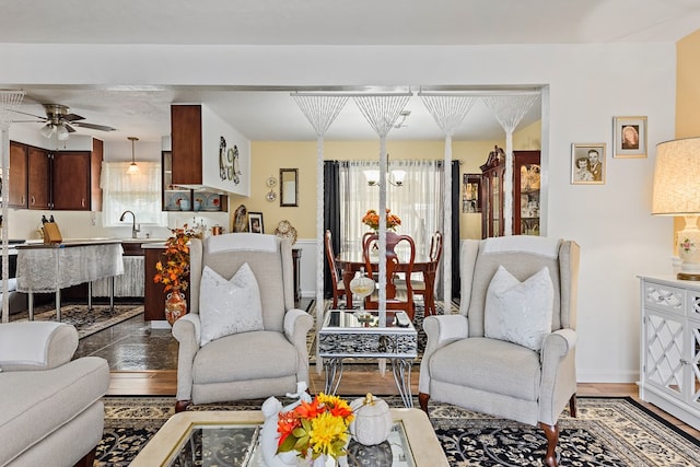 living room with plenty of natural light, sink, wood-type flooring, and ceiling fan with notable chandelier