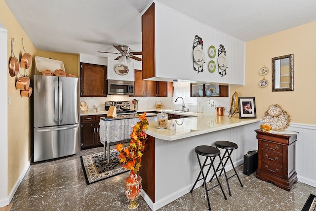 kitchen featuring kitchen peninsula, appliances with stainless steel finishes, dark brown cabinetry, and a kitchen breakfast bar