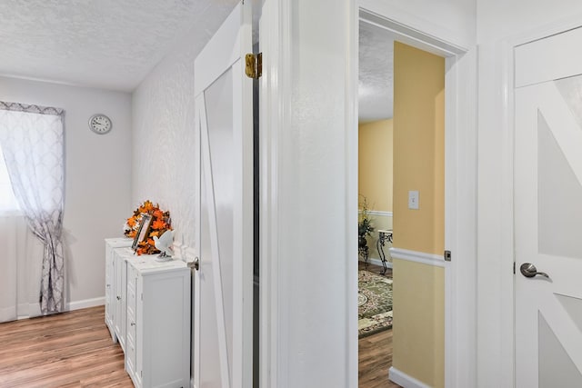 corridor featuring light hardwood / wood-style floors and a textured ceiling