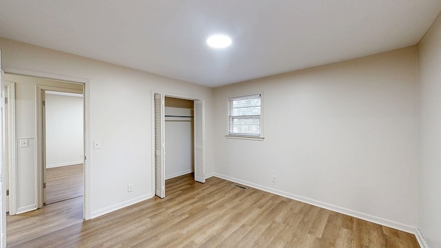 unfurnished bedroom with a closet and light wood-type flooring