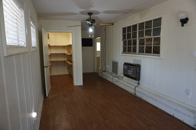 interior space with heating unit, ceiling fan, dark hardwood / wood-style floors, and a healthy amount of sunlight