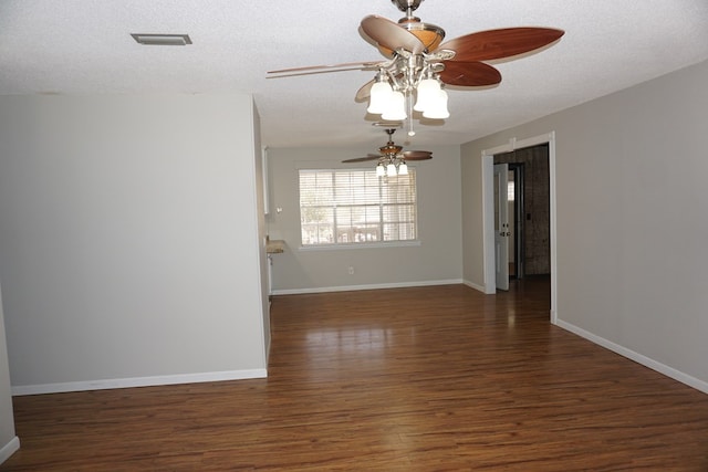 empty room featuring ceiling fan, dark wood-type flooring, and a textured ceiling