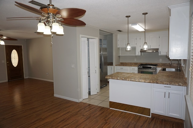 kitchen featuring sink, white cabinetry, wood-type flooring, appliances with stainless steel finishes, and kitchen peninsula