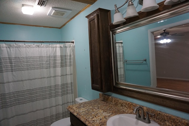 bathroom featuring crown molding, ceiling fan, vanity, a textured ceiling, and toilet