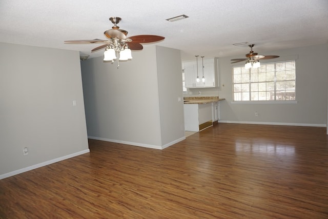 unfurnished living room featuring dark wood-type flooring, ceiling fan, and a textured ceiling