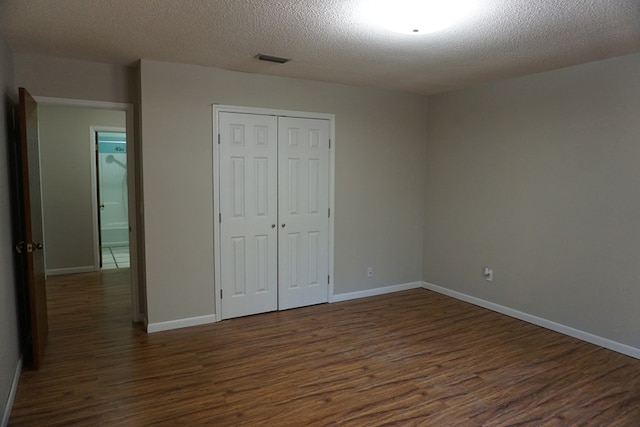 unfurnished bedroom with dark hardwood / wood-style floors, a closet, and a textured ceiling