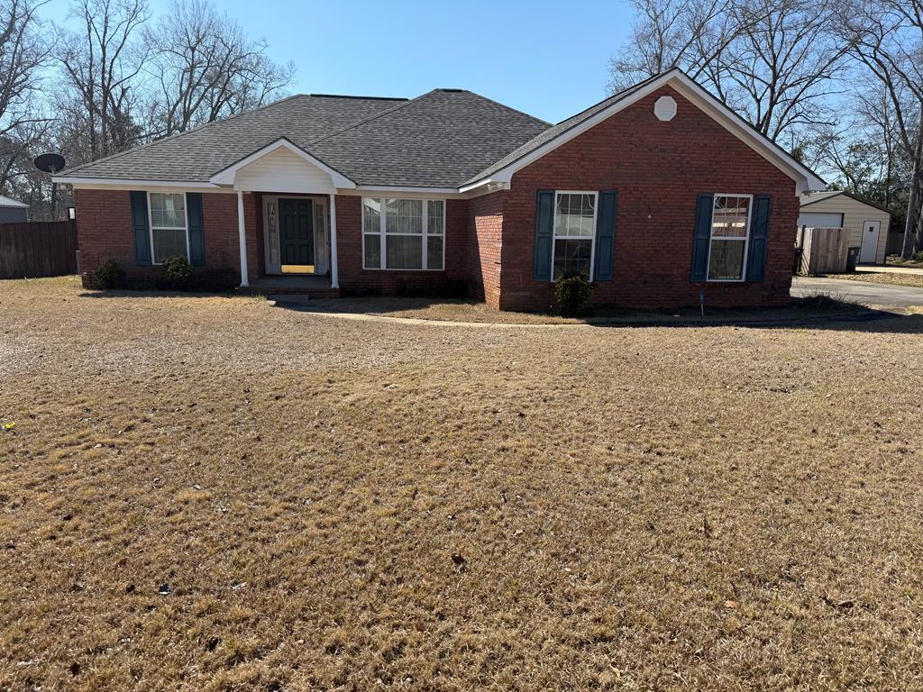 single story home featuring brick siding, fence, and roof with shingles