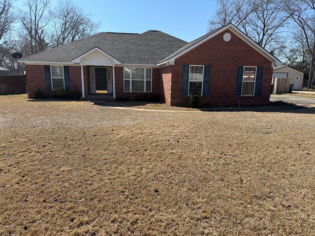 single story home featuring brick siding, fence, and roof with shingles