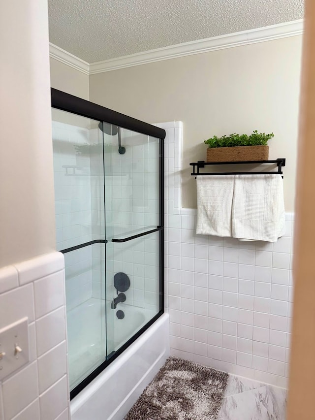 1002 Monterey Ct, Dothan, AL 36303 - bathroom with tile walls, crown molding, combined bath / shower with glass door, a textured ceiling, and a wainscoted wall