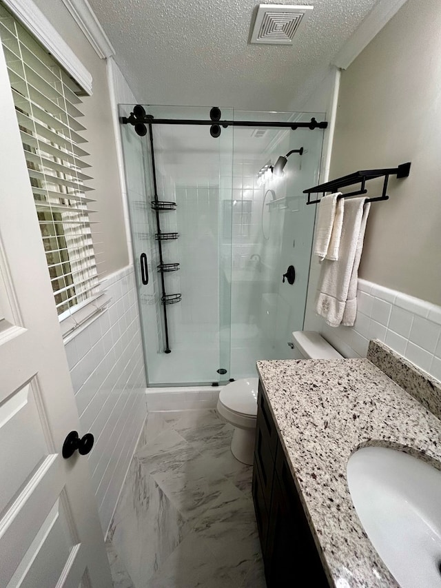 1002 Monterey Ct, Dothan, AL 36303 - bathroom with tile walls, vanity, toilet, a wainscoted wall, and a textured ceiling