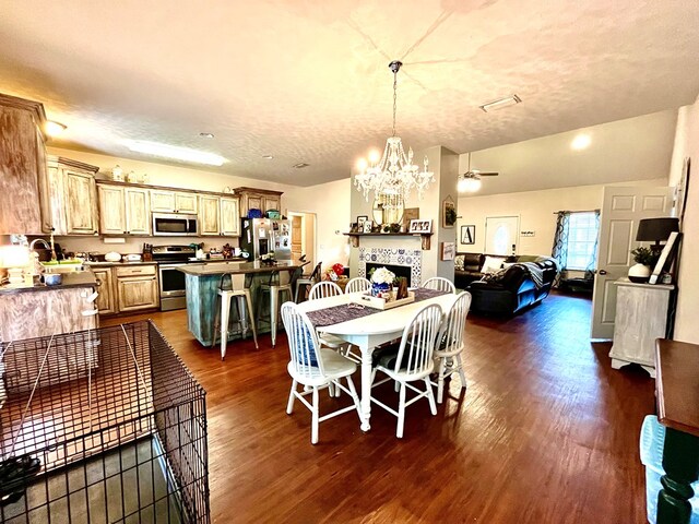 dining space with dark hardwood / wood-style flooring, ceiling fan with notable chandelier, a textured ceiling, sink, and a tiled fireplace