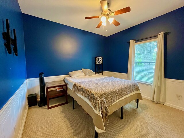 bedroom featuring multiple windows, carpet floors, a nursery area, and ceiling fan