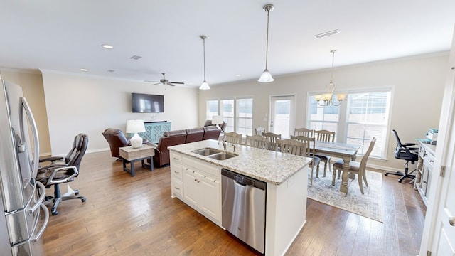 kitchen with a center island with sink, plenty of natural light, stainless steel appliances, light stone countertops, and white cabinets