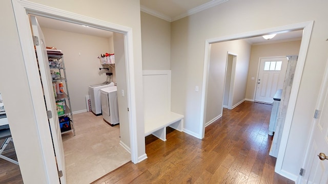 corridor with ornamental molding, light wood-type flooring, and washer and clothes dryer