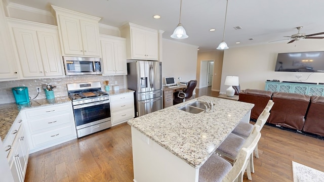 kitchen with tasteful backsplash, a breakfast bar area, hanging light fixtures, stainless steel appliances, and a center island with sink