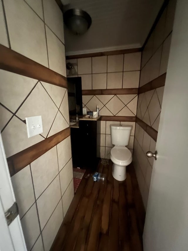 bathroom with toilet, wood-type flooring, and tile walls