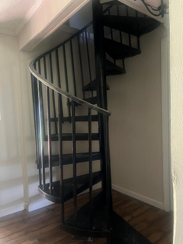 stairway with hardwood / wood-style floors and a textured ceiling