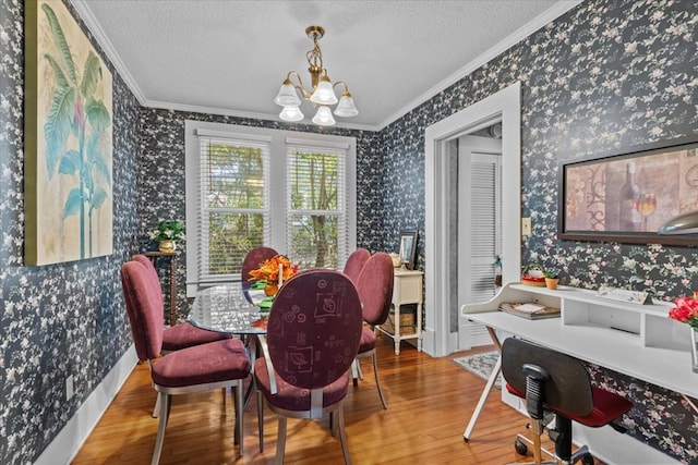 dining area with a textured ceiling, a notable chandelier, wood-type flooring, and ornamental molding