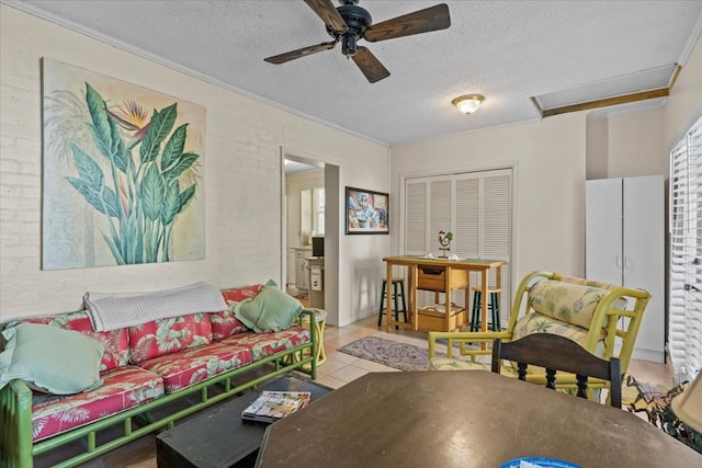 living room with ceiling fan, light tile patterned floors, brick wall, and a textured ceiling