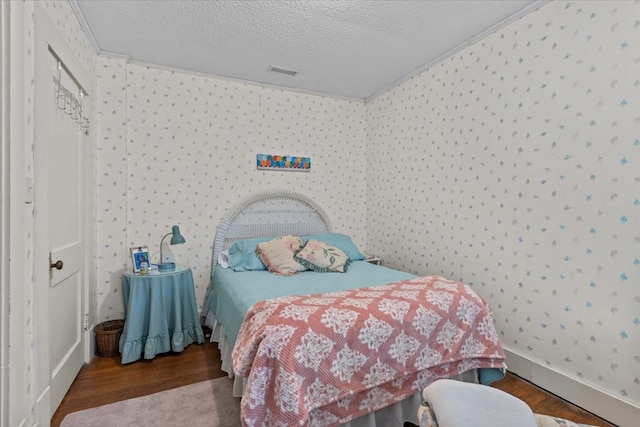 bedroom featuring hardwood / wood-style flooring, crown molding, and a textured ceiling