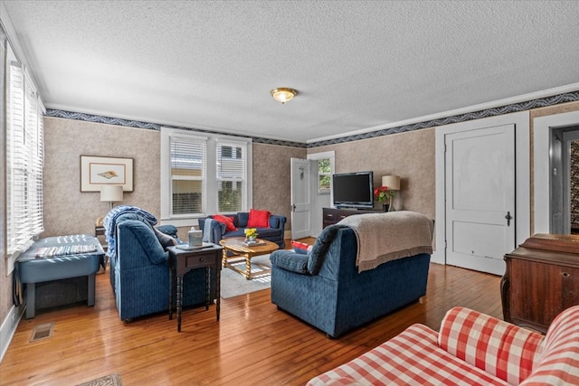 living room featuring wood-type flooring, a textured ceiling, and ornamental molding