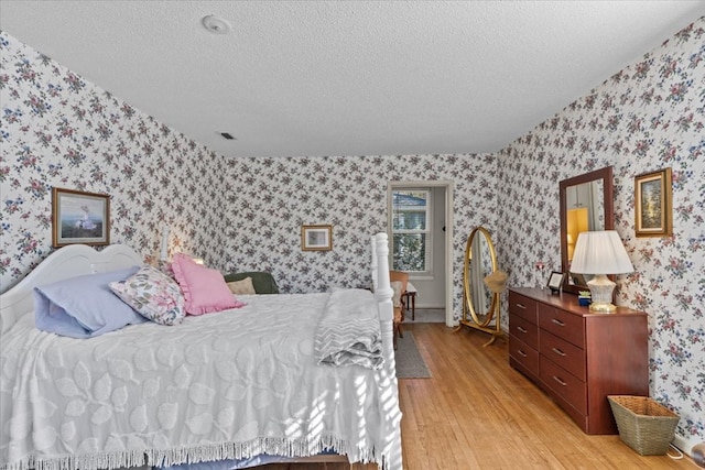 bedroom with light hardwood / wood-style floors and a textured ceiling