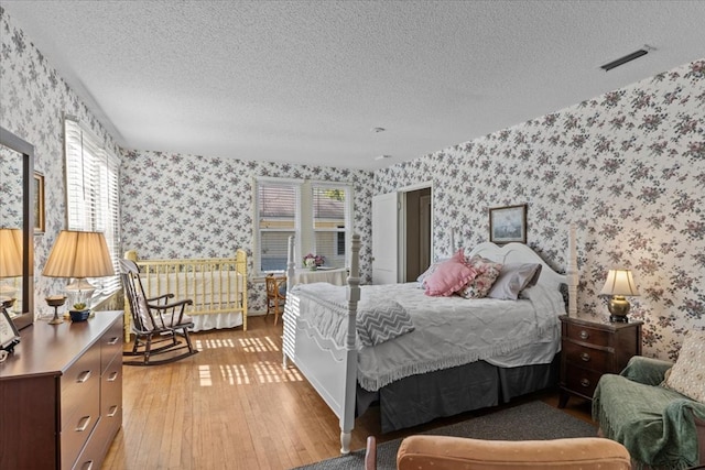 bedroom with light hardwood / wood-style floors and a textured ceiling