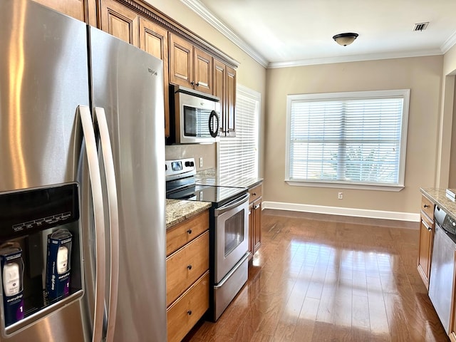 kitchen featuring light stone countertops, ornamental molding, stainless steel appliances, dark wood-type flooring, and brown cabinets