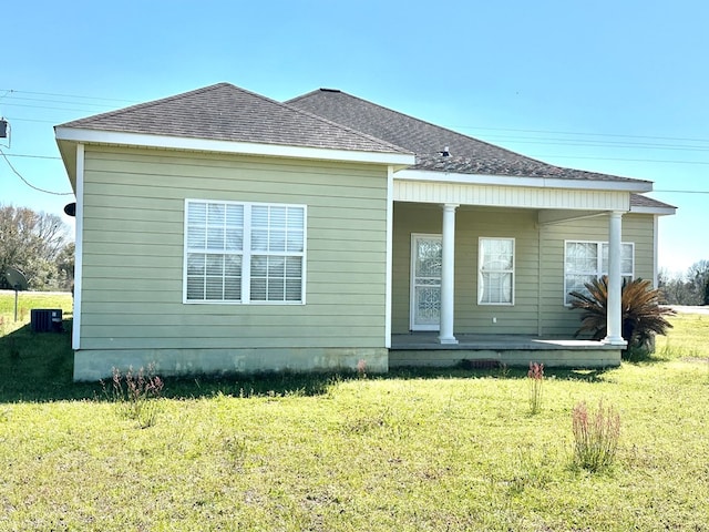 back of house featuring central air condition unit, a yard, covered porch, and a shingled roof