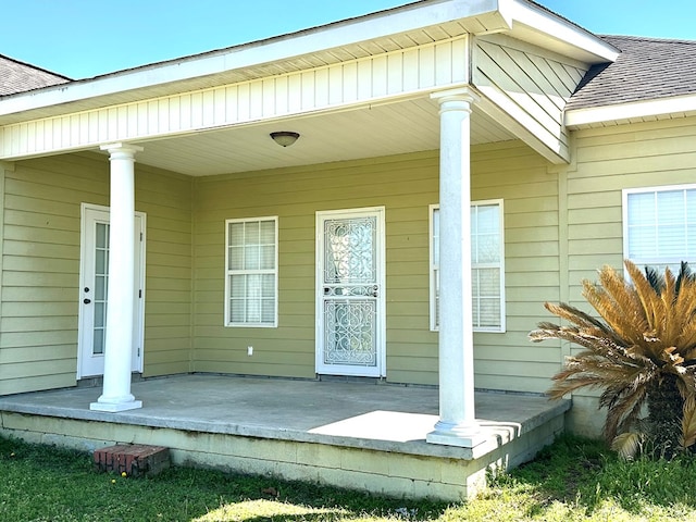 doorway to property featuring a porch and a shingled roof