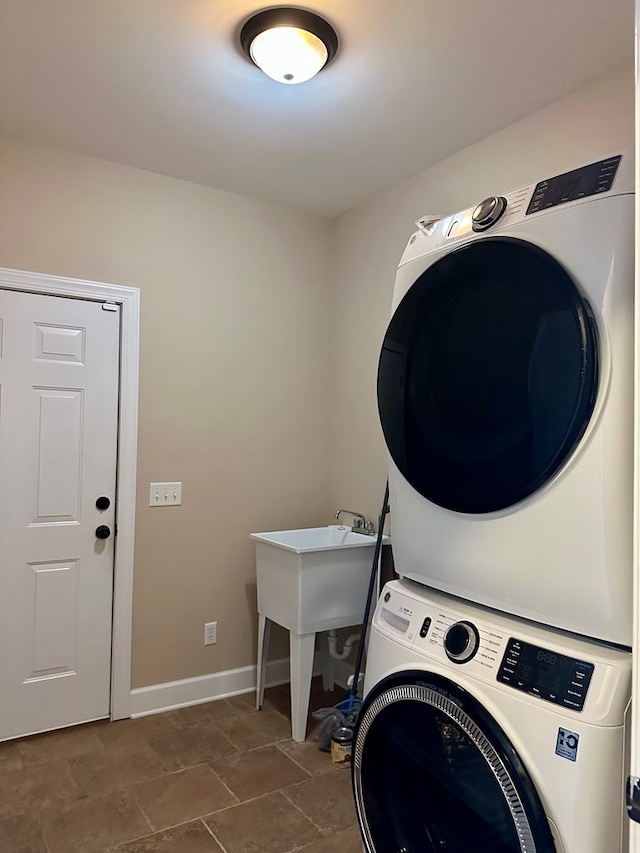 laundry area featuring baseboards, stacked washer and dryer, and laundry area