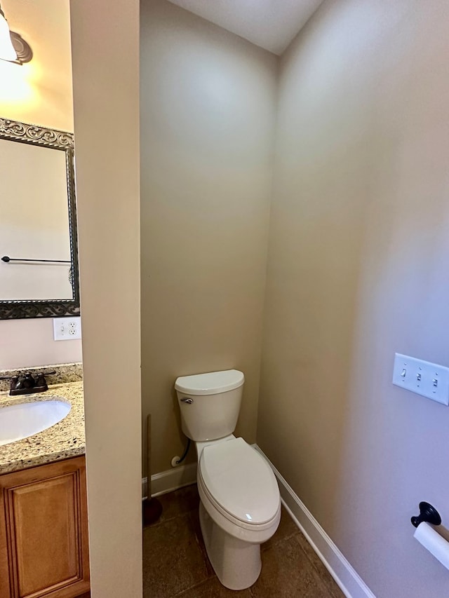 half bath with tile patterned floors, toilet, vanity, and baseboards