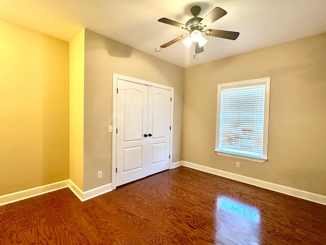 unfurnished bedroom featuring a closet, ceiling fan, baseboards, and wood finished floors