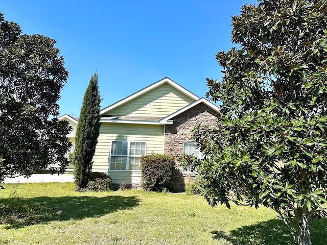 view of home's exterior with stone siding and a yard