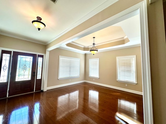 foyer with dark wood-style floors, a raised ceiling, baseboards, and ornamental molding