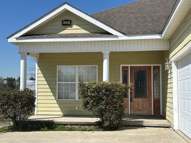 entrance to property featuring covered porch and a shingled roof