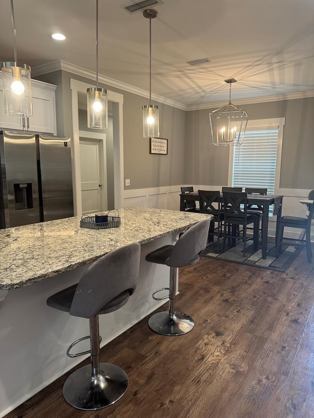 1180 Sandbed Rd, Newton, AL 36352 - kitchen featuring stainless steel refrigerator with ice dispenser, white cabinetry, dark wood-type flooring, a kitchen breakfast bar, and light stone countertops