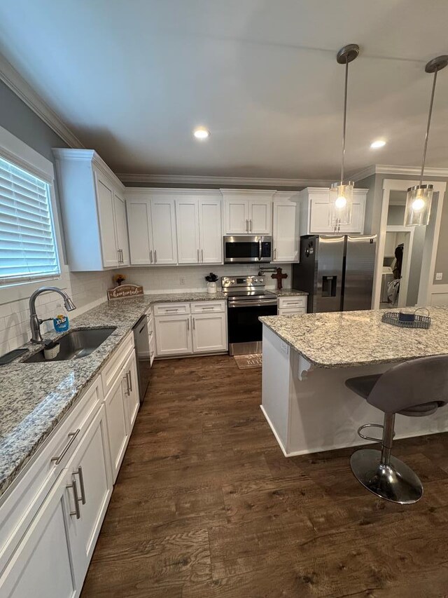 1180 Sandbed Rd, Newton, AL 36352 - kitchen with appliances with stainless steel finishes, a sink, ornamental molding, white cabinetry, and a breakfast bar