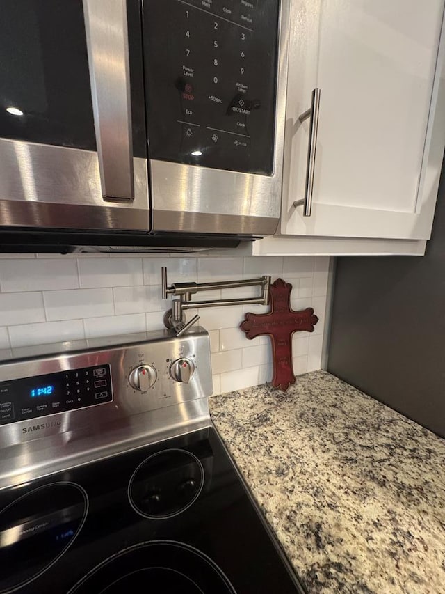 1180 Sandbed Rd, Newton, AL 36352 - kitchen view of appliances with stainless steel finishes, decorative backsplash, white cabinets, light stone counters, and pot filler